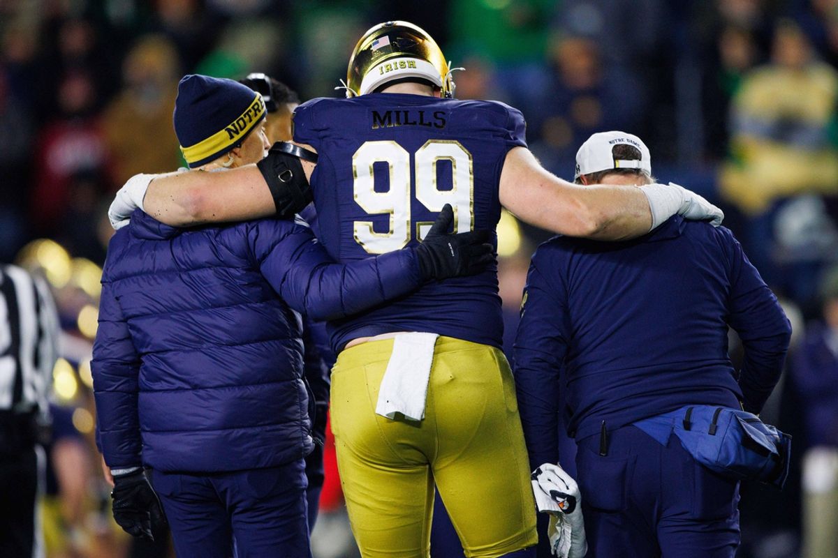 Notre Dame defensive lineman Rylie Mills (99) is helped off the field during the first round of the College Football Playoff between Notre Dame and Indiana at Notre Dame Stadium on Friday, Dec. 20, 2024, in South Bend.