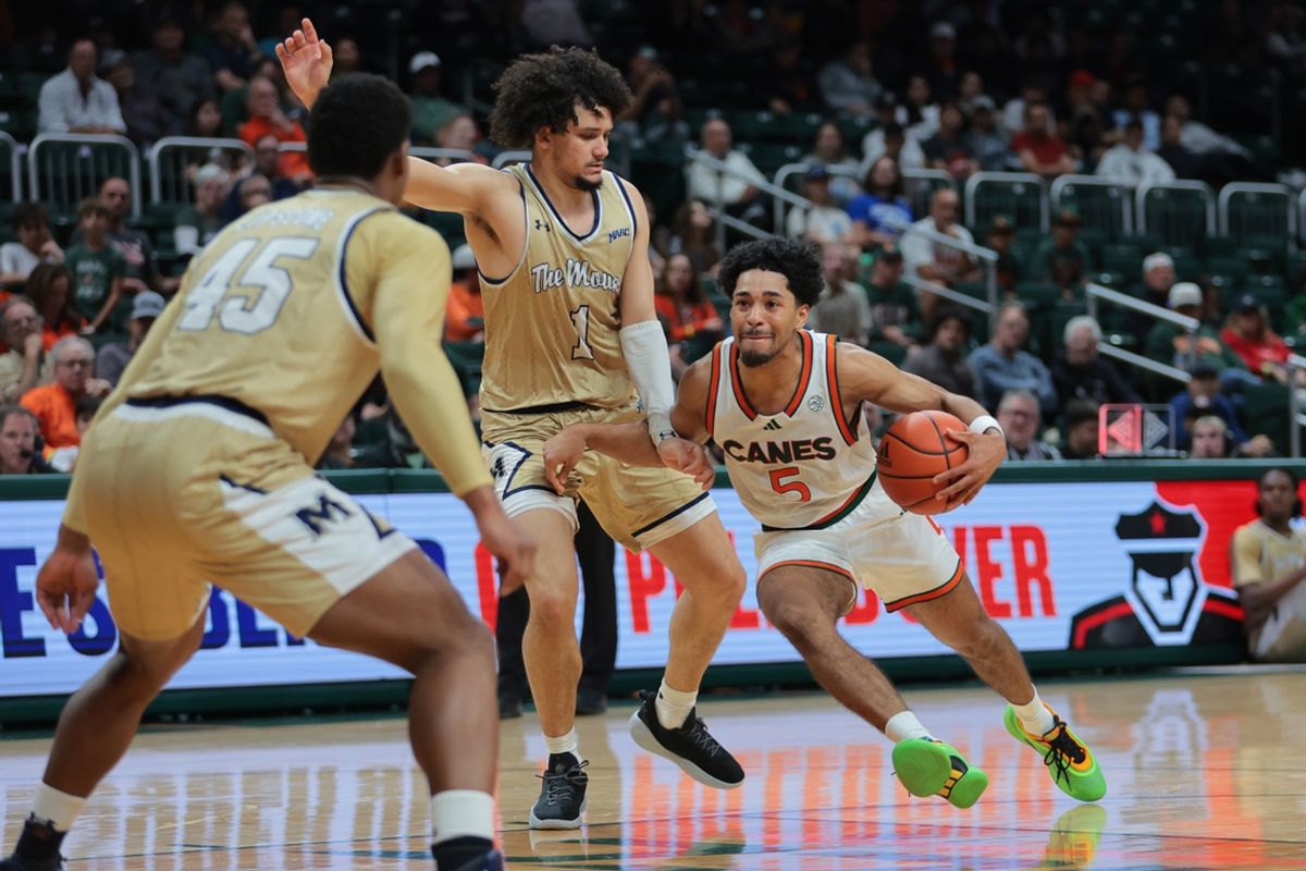Dec 21, 2024; Coral Gables, Florida, USA; Miami Hurricanes guard Jalen Blackmon (5) drives to the basket past Mount St. Mary's Mountaineers guard Carmelo Pacheco (1) during the second half at Watsco Center. Mandatory Credit: Sam Navarro-Imagn Images