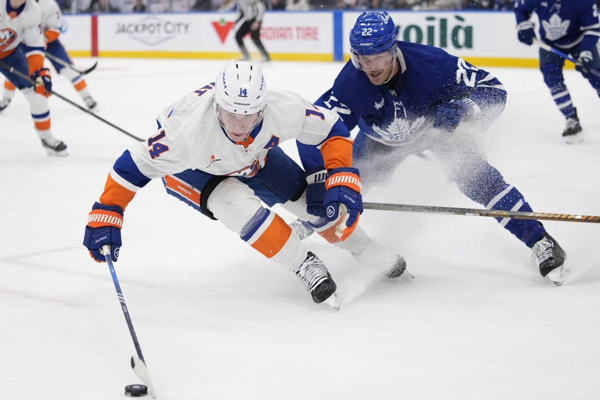 Dec 21, 2024; Toronto, Ontario, CAN; New York Islanders forward Bo Horvat (14) tries to control the puck against Toronto Maple Leafs defenceman Jake McCabe (22) during the second period at Scotiabank Arena. Mandatory Credit: John E. Sokolowski-Imagn Images