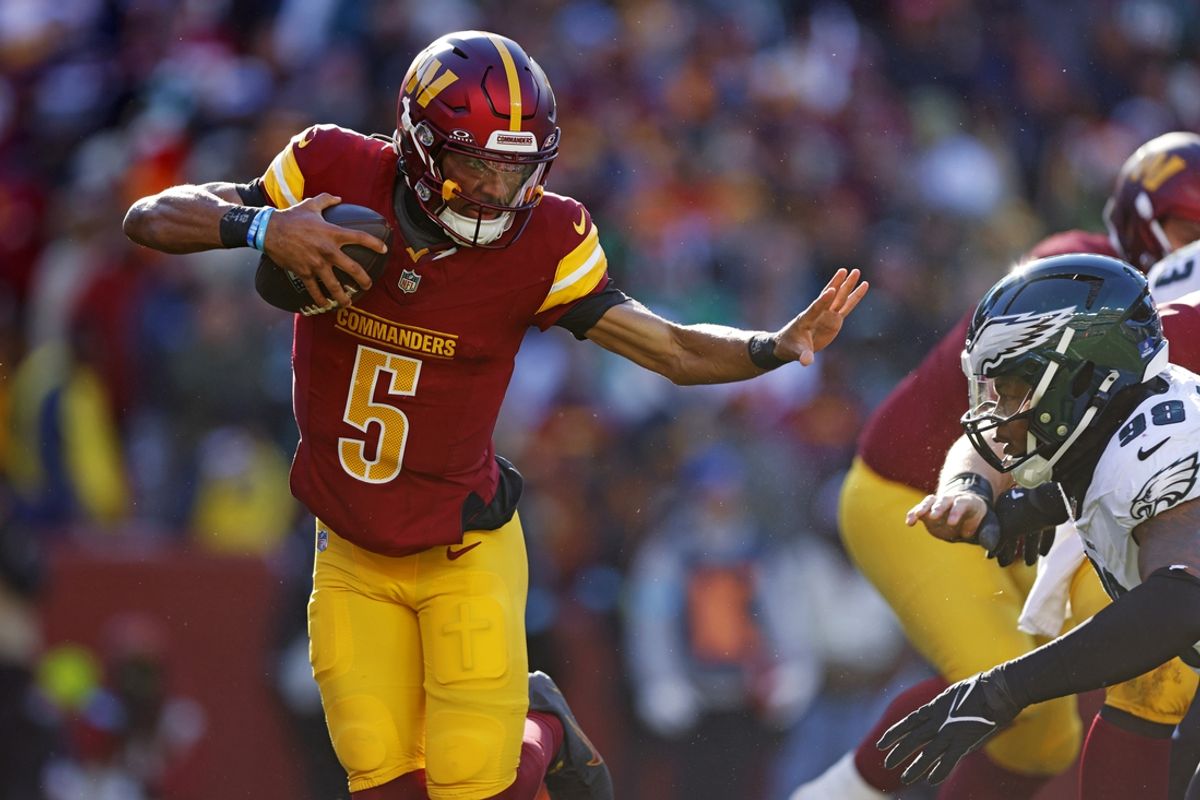 Dec 22, 2024; Landover, Maryland, USA; Washington Commanders quarterback Jayden Daniels (5) runs the ball against Philadelphia Eagles defensive tackle Jalen Carter (98) during the first quarter at Northwest Stadium. Mandatory Credit: Peter Casey-Imagn Images