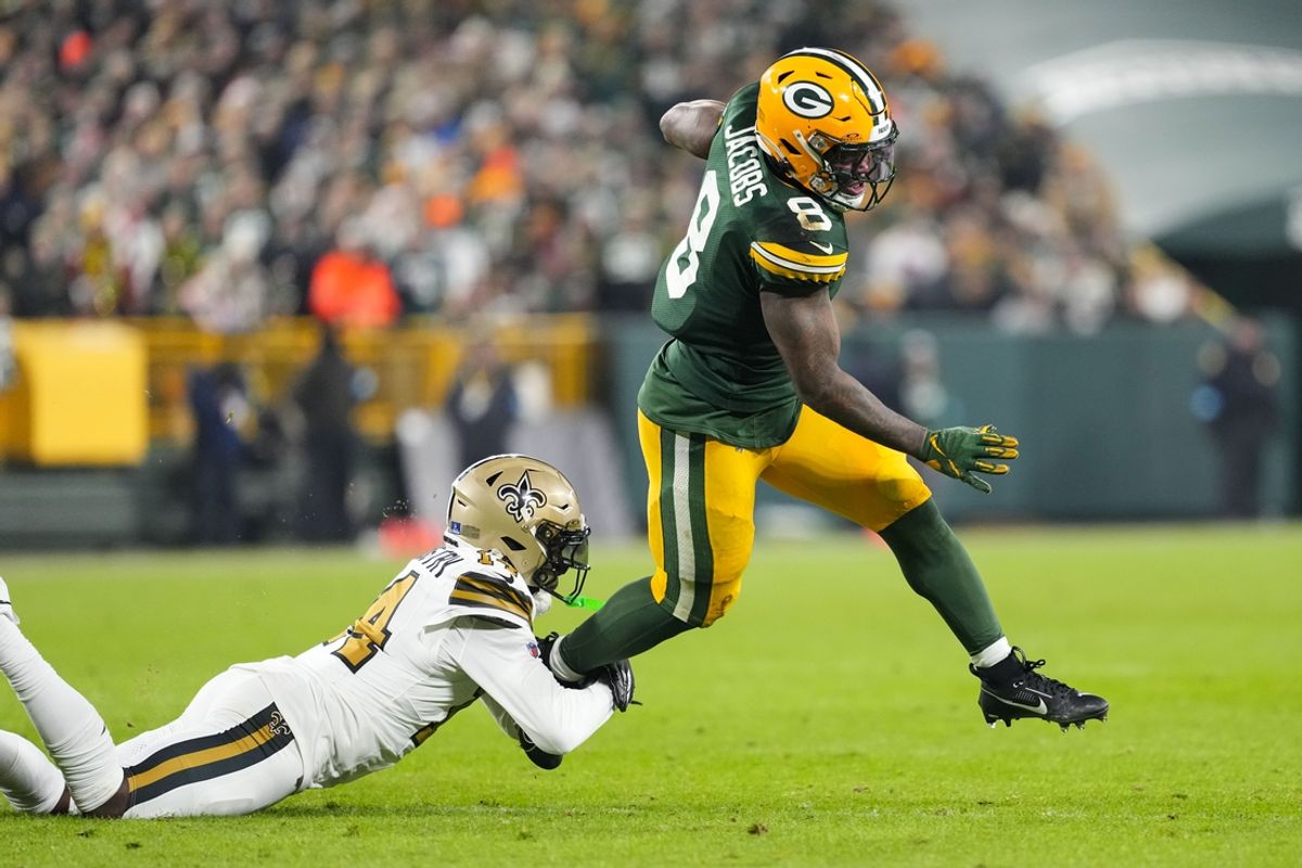 Dec 23, 2024; Green Bay, Wisconsin, USA;  Green Bay Packers running back Josh Jacobs (8) rushes with the football as New Orleans Saints cornerback Kool-Aid McKinstry (14) defends during the second quarter at Lambeau Field. Mandatory Credit: Jeff Hanisch-Imagn Images
