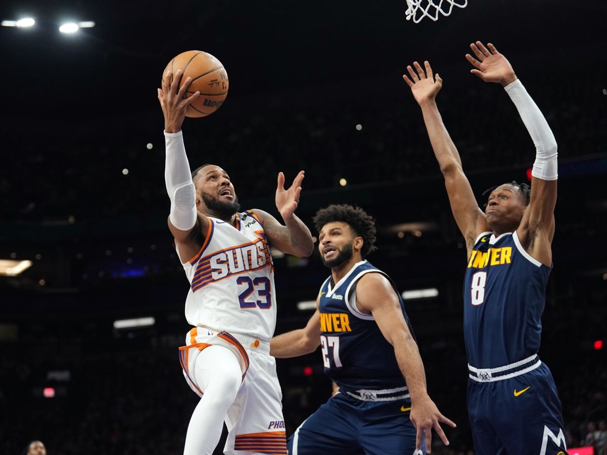 Dec 25, 2024; Phoenix, Arizona, USA; Phoenix Suns guard Monte Morris (23) puts up a layup over Denver Nuggets guard Jamal Murray (27) and Denver Nuggets forward Peyton Watson (8) during the first half at Footprint Center. Mandatory Credit: Joe Camporeale-Imagn Images