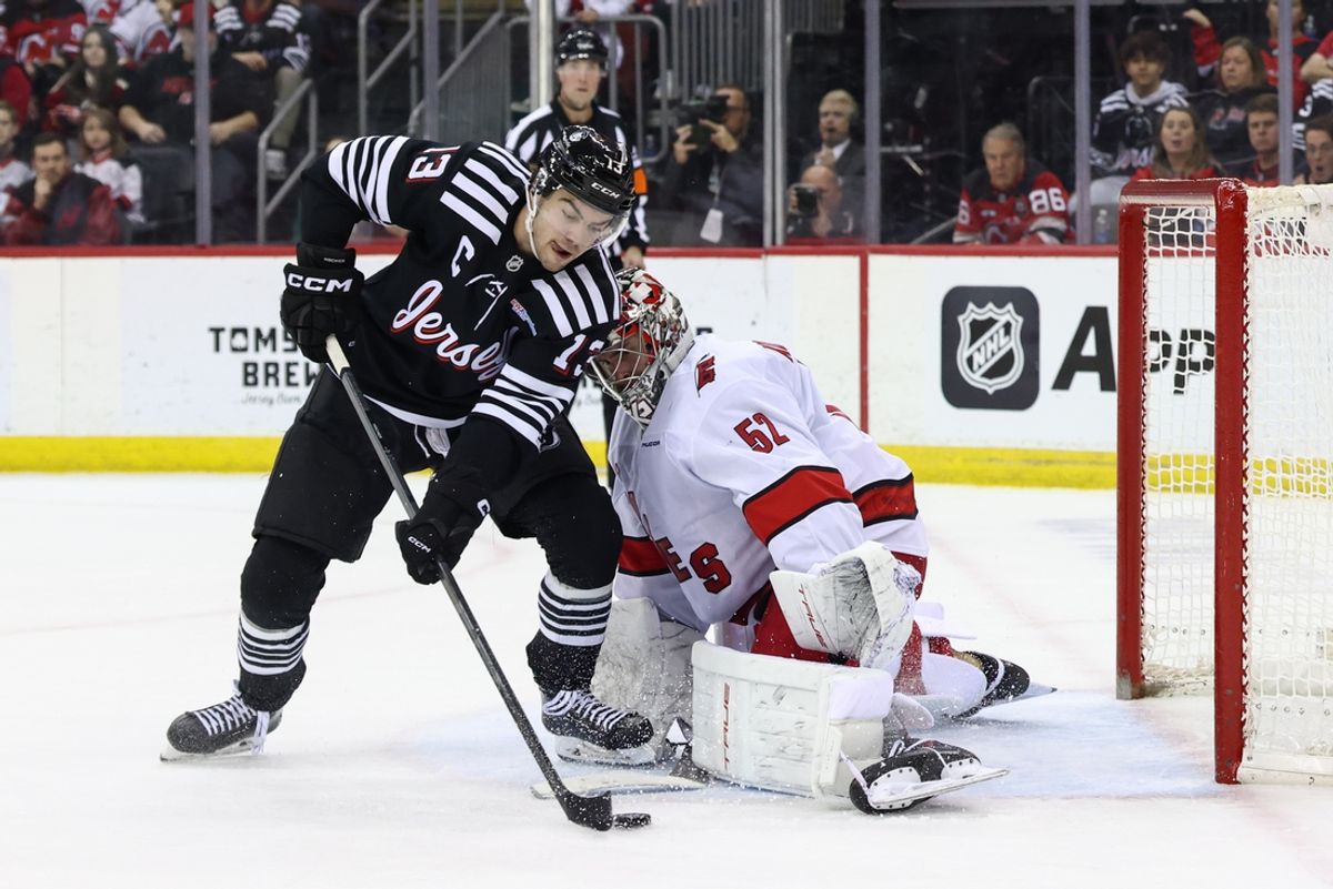 Dec 27, 2024; Newark, New Jersey, USA; Carolina Hurricanes goaltender Pyotr Kochetkov (52) makes a save on New Jersey Devils center Nico Hischier (13) during the second period at Prudential Center. Mandatory Credit: Ed Mulholland-Imagn Images