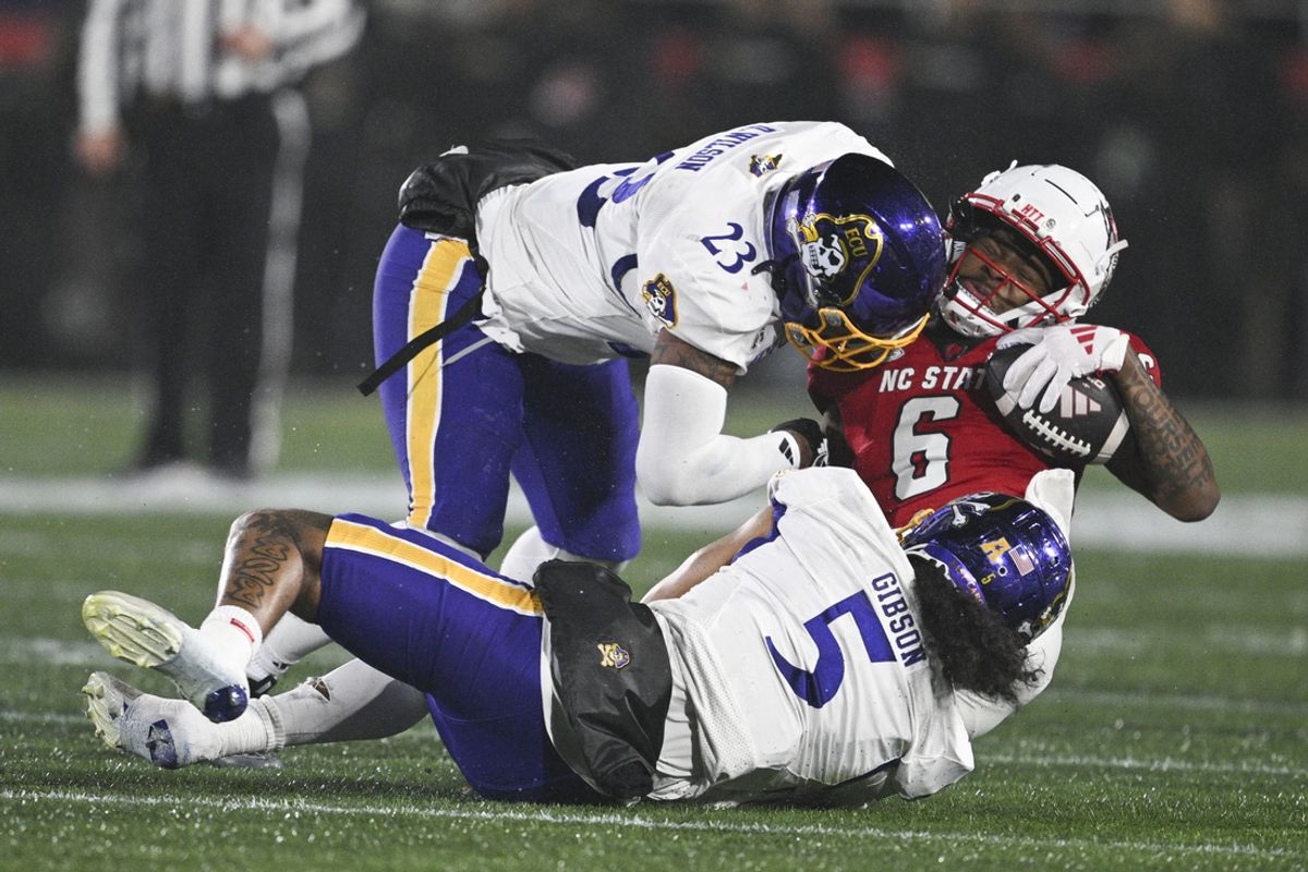 Dec 28, 2024; Annapolis, MD, USA; North Carolina State Wolfpack wide receiver Wesley Grimes (6) is hit by East Carolina Pirates linebacker Dameon Wilson (23) and Pirates defensive back Gavin Gibson (5)  during the first half of the Go Bowling Military Bowl at Navy-Marine Corps Memorial Stadium. Mandatory Credit: Tommy Gilligan-Imagn Images