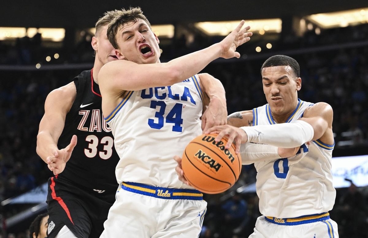 Dec 28, 2024; Inglewood, California, USA; UCLA Bruins forward Tyler Bilodeau (34) and guard Kobe Johnson (0) reach for a rebound past Gonzaga Bulldogs forward Ben Gregg (33) during the second half at Intuit Dome. Mandatory Credit: Robert Hanashiro-Imagn Images