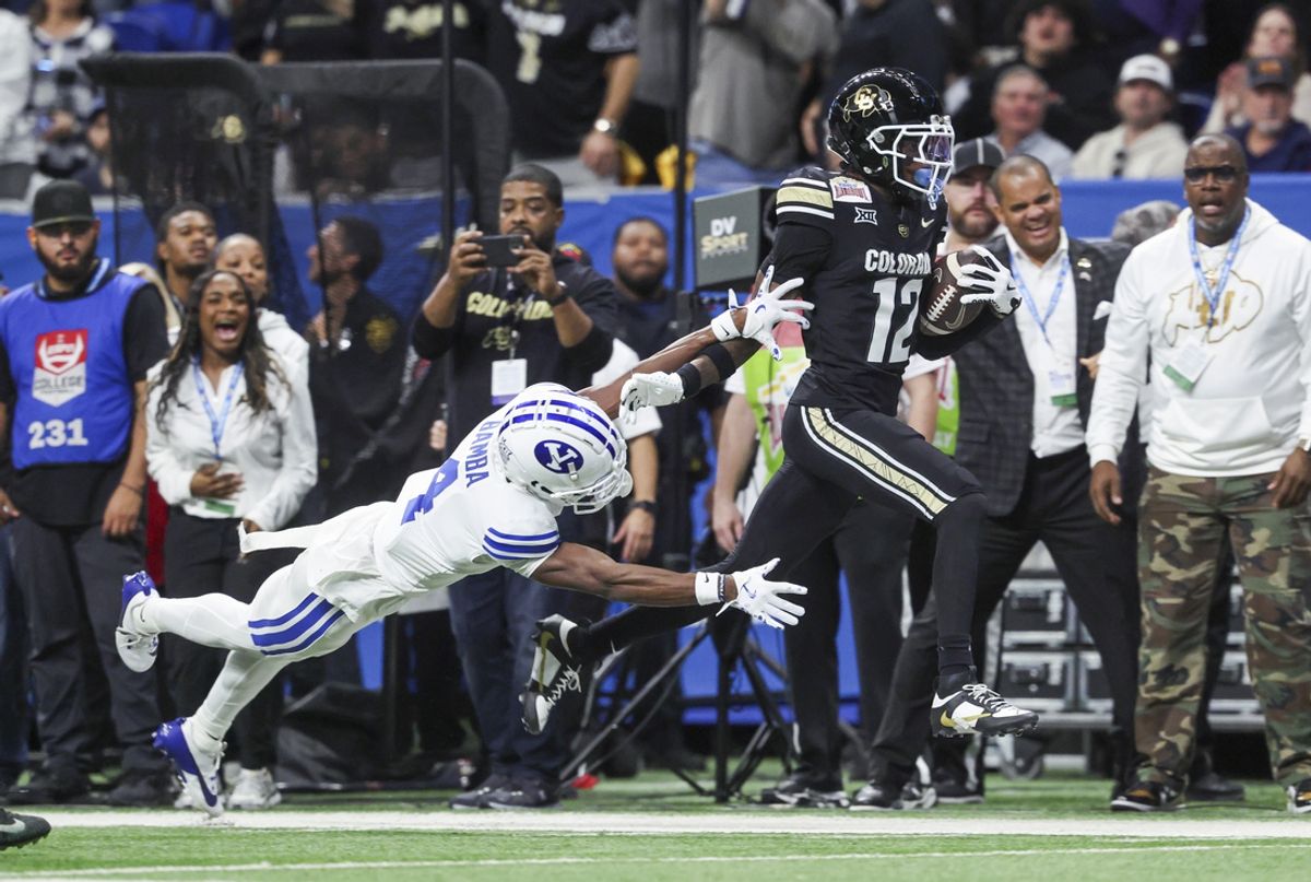 Colorado Buffaloes wide receiver Travis Hunter (12) runs with the ball as Brigham Young Cougars cornerback Mory Bamba (4) attempts to make a tackle during the second quarter at Alamodome. Mandatory Credit: Troy Taormina-Imagn Images