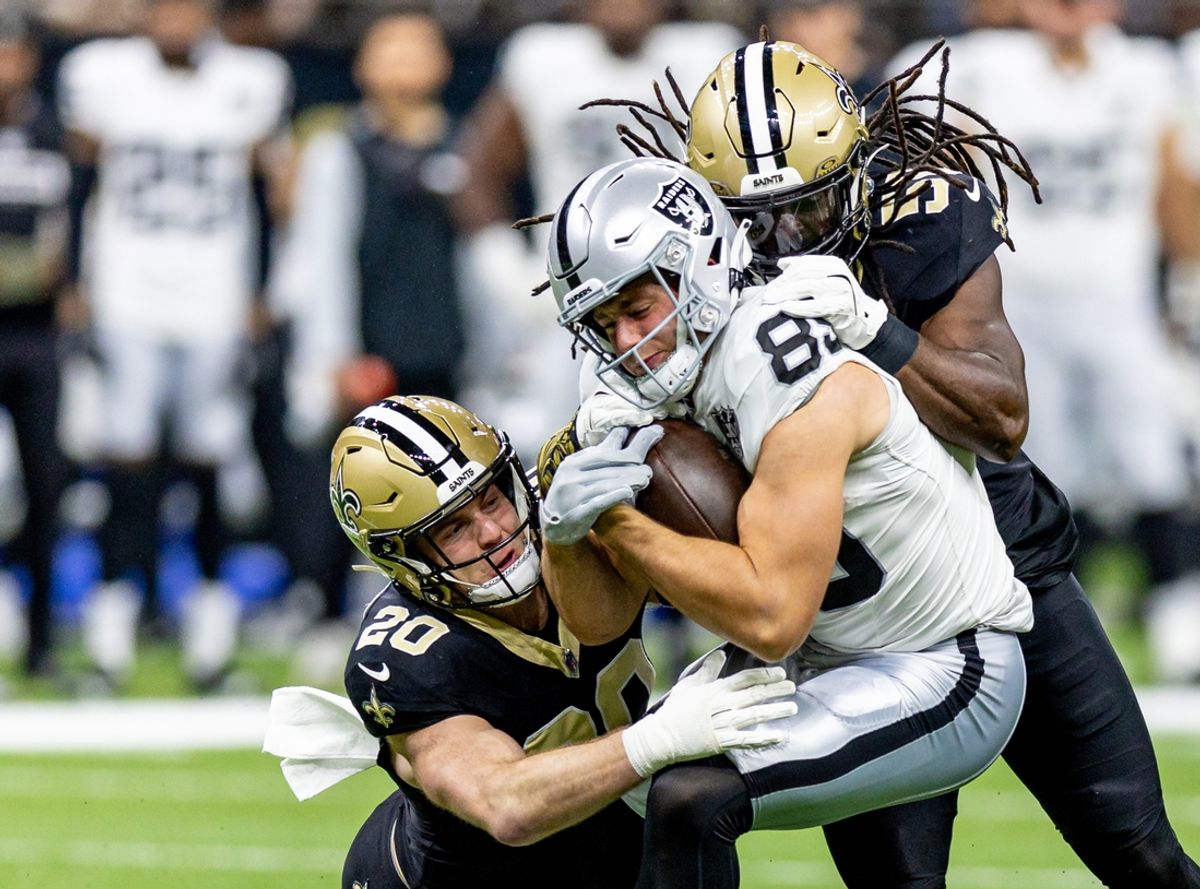 Dec 29, 2024; New Orleans, Louisiana, USA;  New Orleans Saints linebacker Pete Werner (20) and linebacker Demario Davis (56) tackle Las Vegas Raiders tight end Brock Bowers (89) during the first half at Caesars Superdome. Mandatory Credit: Stephen Lew-Imagn Images