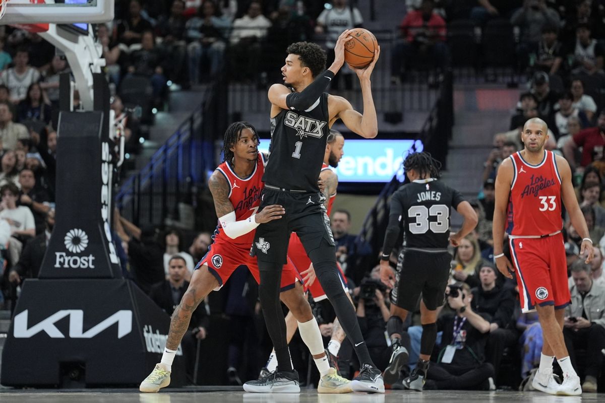 Dec 31, 2024; San Antonio, Texas, USA;  San Antonio Spurs center Victor Wembanyama (1) looks to pass against LA Clippers guard Kevin Porter Jr. (77) in the first half at Frost Bank Center. Mandatory Credit: Daniel Dunn-Imagn Images