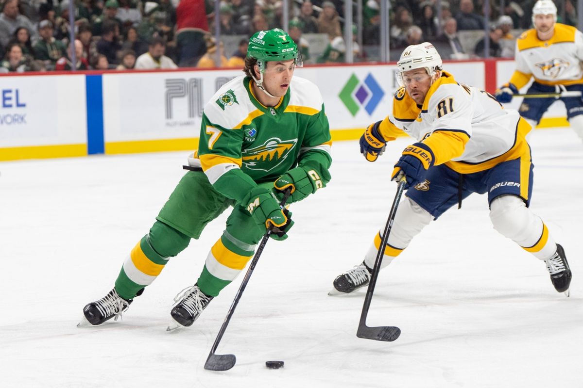 Dec 31, 2024; Saint Paul, Minnesota, USA; Minnesota Wild defenseman Brock Faber (7) skates with the puck defended by Nashville Predators center Jonathan Marchessault (81) in the first period at Xcel Energy Center. Mandatory Credit: Matt Blewett-Imagn Images
