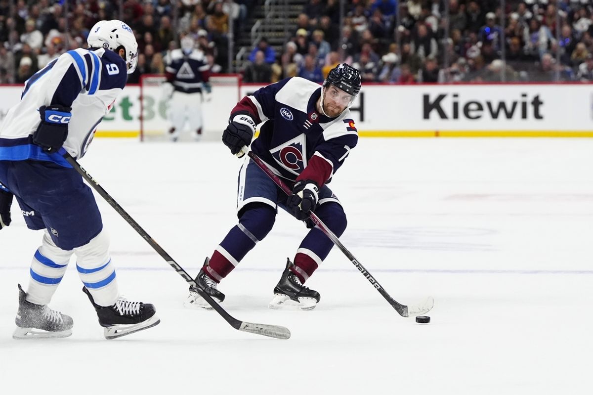 Dec 31, 2024; Denver, Colorado, USA; Colorado Avalanche defenseman Devon Toews (7) bases the puck Winnipeg Jets left wing Alex Iafallo (9) in the second period at Ball Arena. Mandatory Credit: Ron Chenoy-Imagn Images