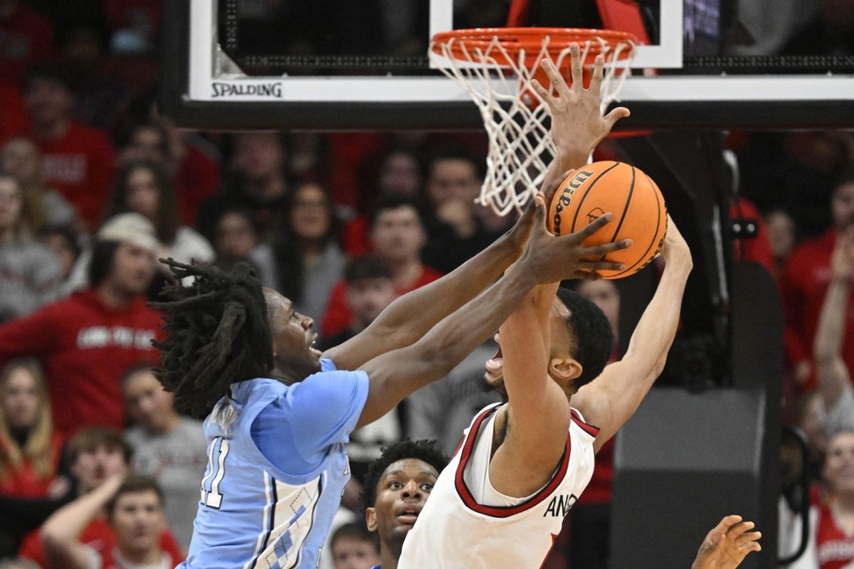 Jan 1, 2025; Louisville, Kentucky, USA;  North Carolina Tar Heels guard Ian Jackson (11) grabs a rebound over Louisville Cardinals center Frank Anselem-Ibe (13) during the first half at KFC Yum! Center. Mandatory Credit: Jamie Rhodes-Imagn Images
