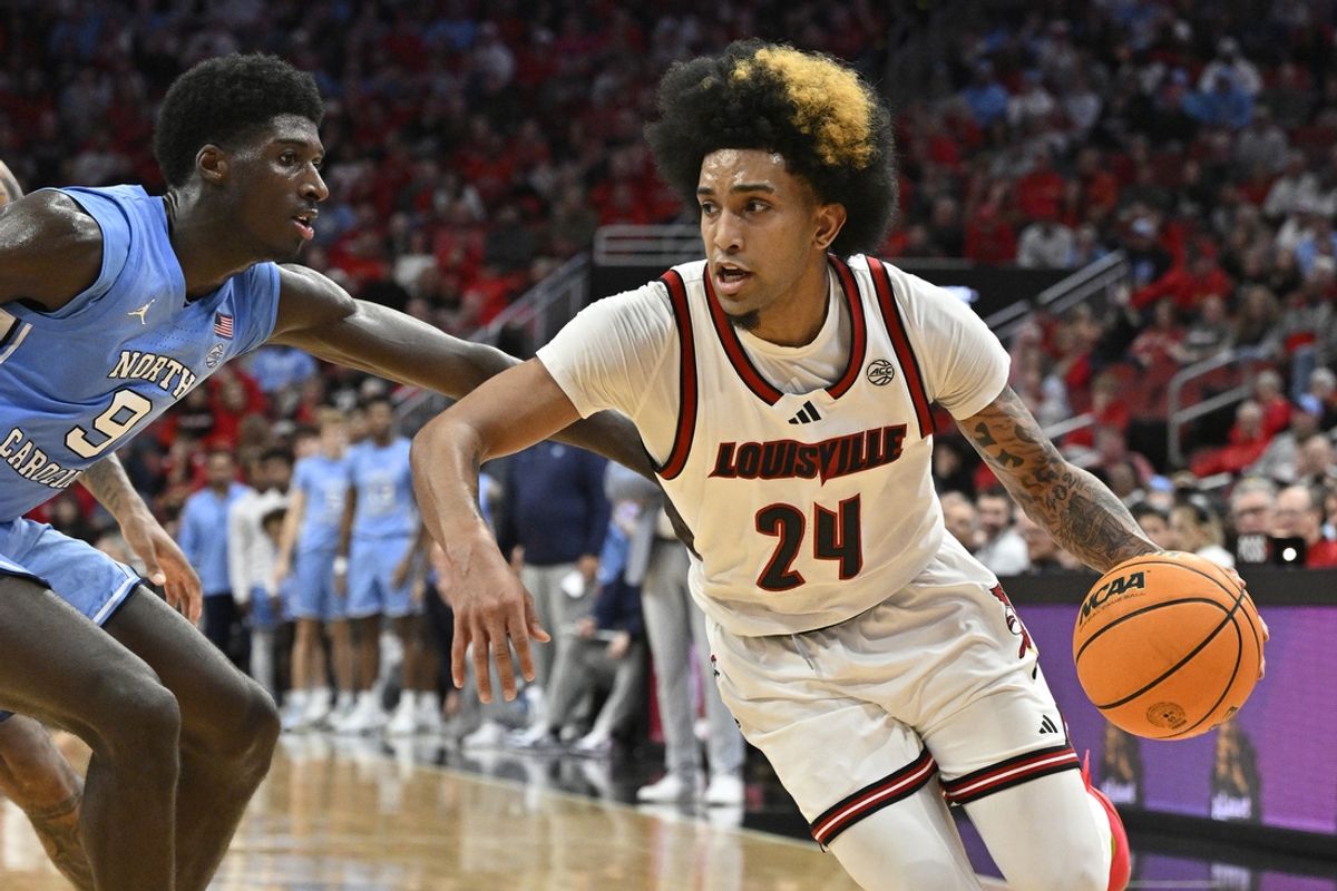 Jan 1, 2025; Louisville, Kentucky, USA;  Louisville Cardinals guard Chucky Hepburn (24) dribbles against North Carolina Tar Heels guard Drake Powell (9) during the second half at KFC Yum! Center. Mandatory Credit: Jamie Rhodes-Imagn Images