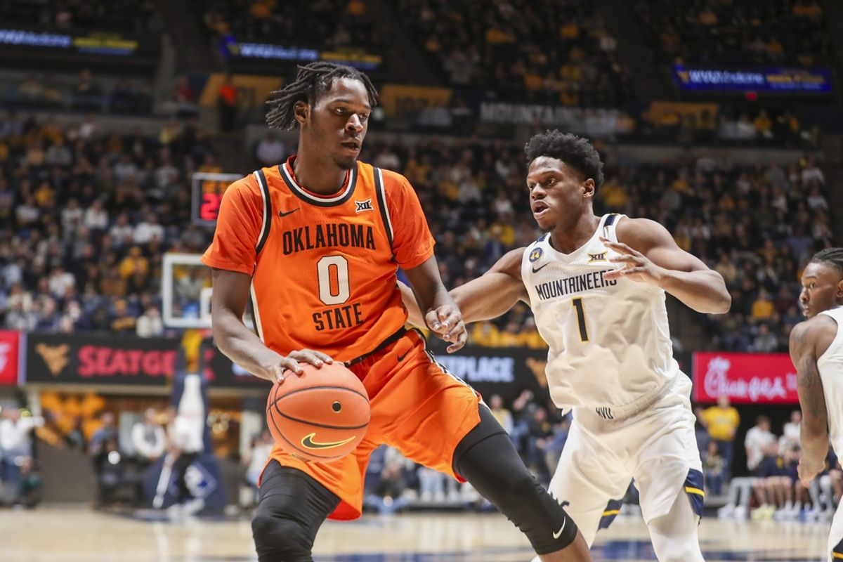 Jan 4, 2025; Morgantown, West Virginia, USA; Oklahoma State Cowboys forward Marchelus Avery (0) dribbles against West Virginia Mountaineers guard Joseph Yesufu (1) during the second half at WVU Coliseum. Mandatory Credit: Ben Queen-Imagn Images