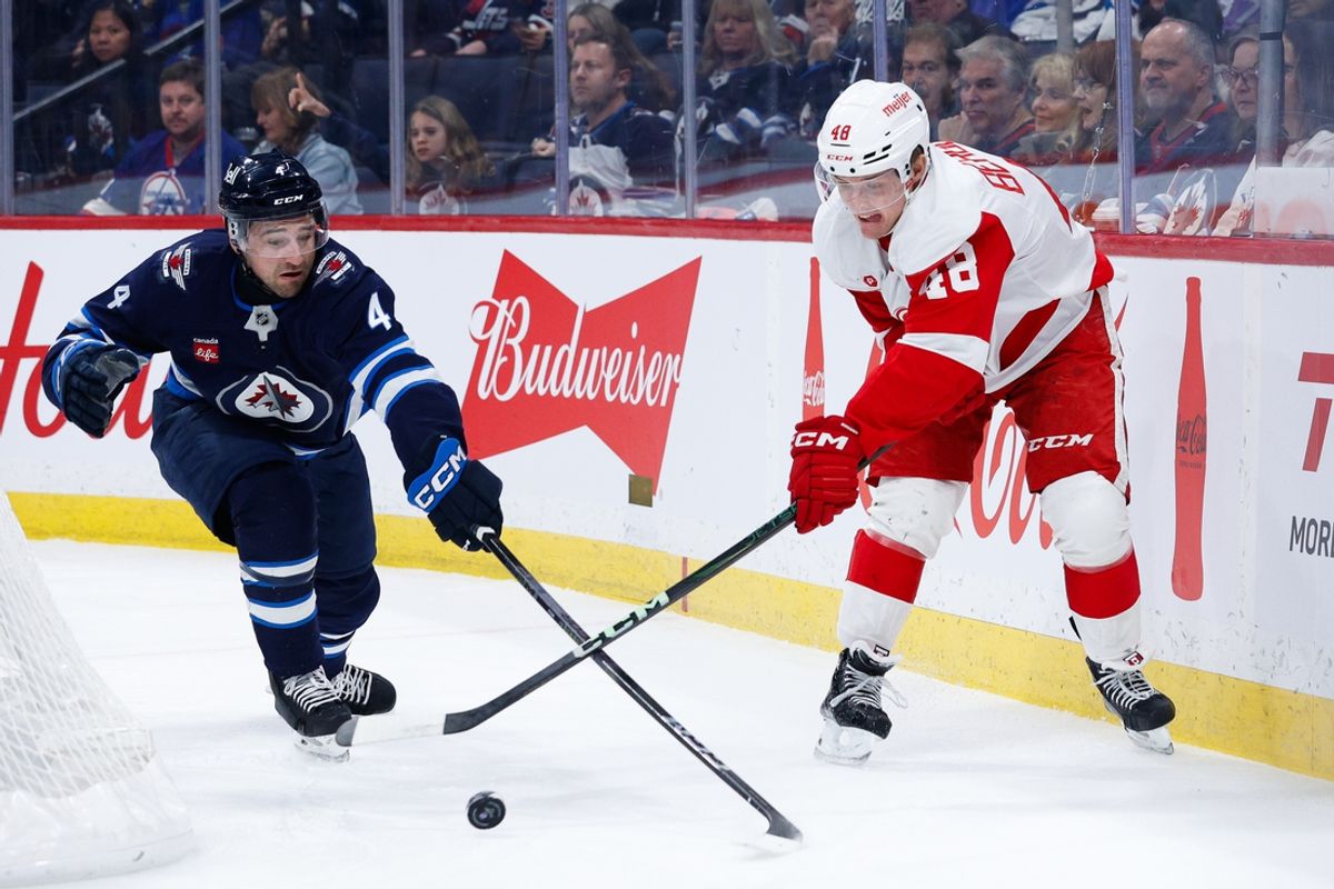 Jan 4, 2025; Winnipeg, Manitoba, CAN;  Detroit Red Wings forward Jonathan Berggen (48) and Winnipeg Jets defenseman Dylan DeMelo (2) battle for the puck during the first period at Canada Life Centre. Mandatory Credit: Terrence Lee-Imagn Images