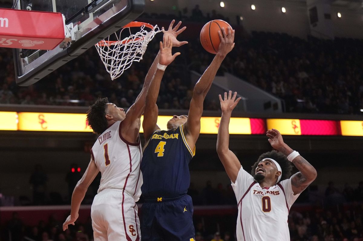 Jan 4, 2025; Los Angeles, California, USA; Michigan Wolverines guard Nimari Burnett (4) shoots the ball against Southern California Trojans guard Desmond Claude (1) and forward Saint Thomas (0) in the first half at Galen Center. Mandatory Credit: Kirby Lee-Imagn Images