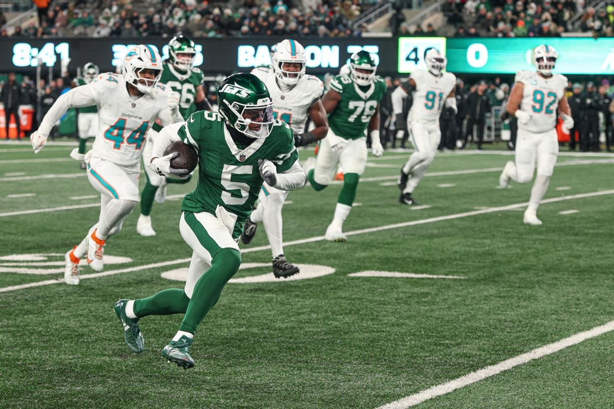 Jan 5, 2025; East Rutherford, New Jersey, USA; New York Jets wide receiver Garrett Wilson (5) gains yards after catch as Miami Dolphins linebacker Chop Robinson (44) pursues during the first half at MetLife Stadium. Mandatory Credit: Vincent Carchietta-Imagn Images