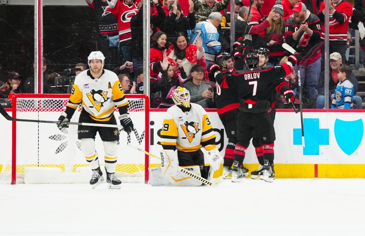 Jan 5, 2025; Raleigh, North Carolina, USA;  Carolina Hurricanes center Sebastian Aho (20) is congratulated after his game winning goal in the overtime by center Martin Necas (88) and defenseman Dmitry Orlov (7) as Pittsburgh Penguins goaltender Alex Nedeljkovic (39) and defenseman Kris Letang (58) look on at Lenovo Center. Mandatory Credit: James Guillory-Imagn Images