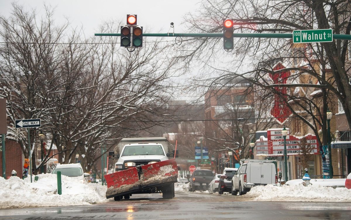 A plow waits at a stop light. Texas could be hit with up to six inches of snow before the Cotton Bowl is played in Arlington on Friday.