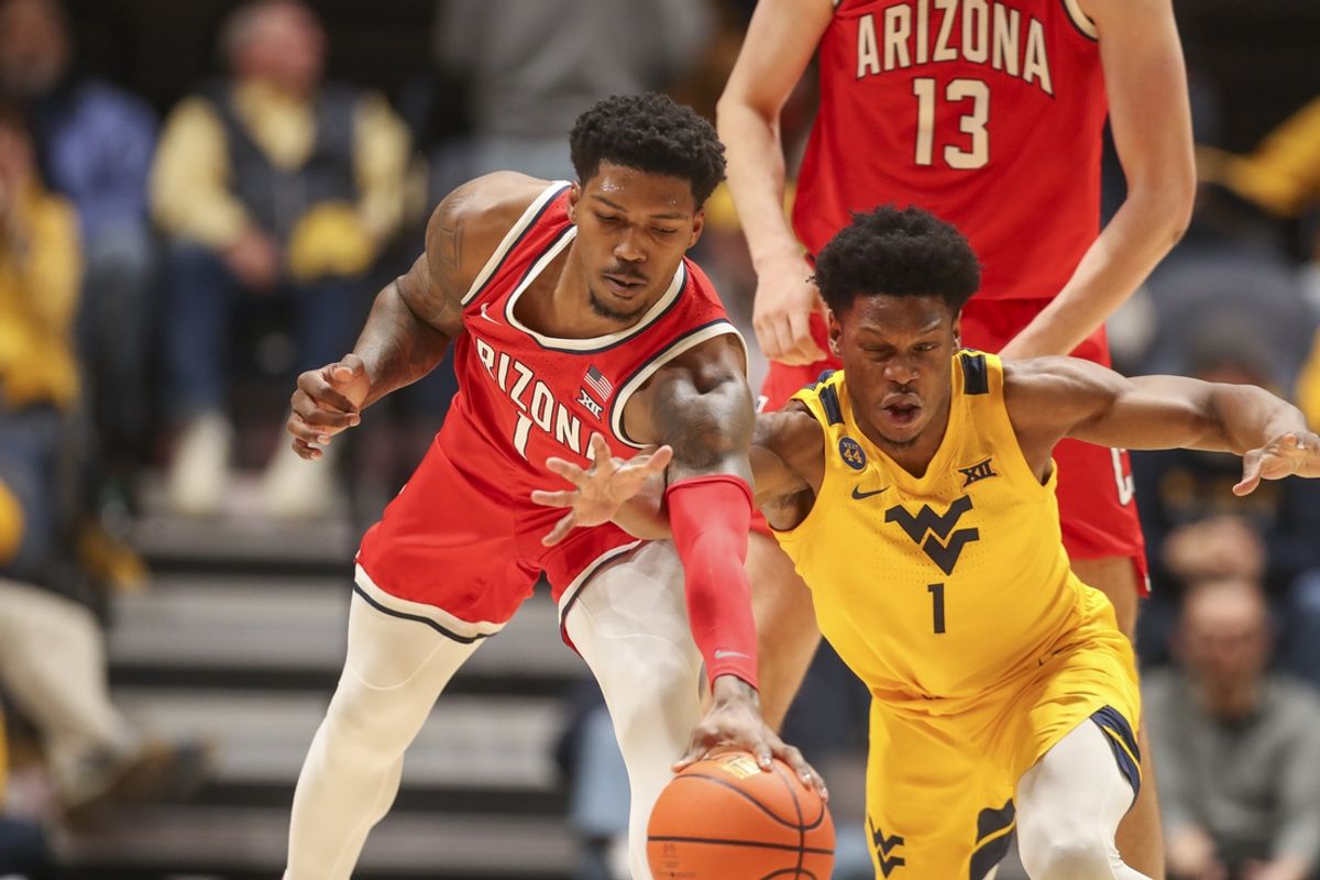 Jan 7, 2025; Morgantown, West Virginia, USA; Arizona Wildcats guard Caleb Love (1) and West Virginia Mountaineers guard Joseph Yesufu (1) fight for a loose ball during the first half at WVU Coliseum. Mandatory Credit: Ben Queen-Imagn Images