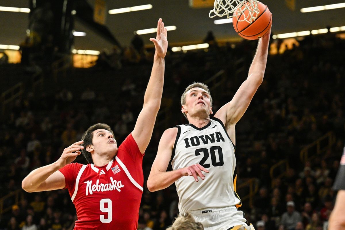Jan 7, 2025; Iowa City, Iowa, USA; Iowa Hawkeyes forward Payton Sandfort (20) goes to the basket as Nebraska Cornhuskers forward Berke Buyuktuncel (9) defends during the second half at Carver-Hawkeye Arena. Mandatory Credit: Jeffrey Becker-Imagn Images