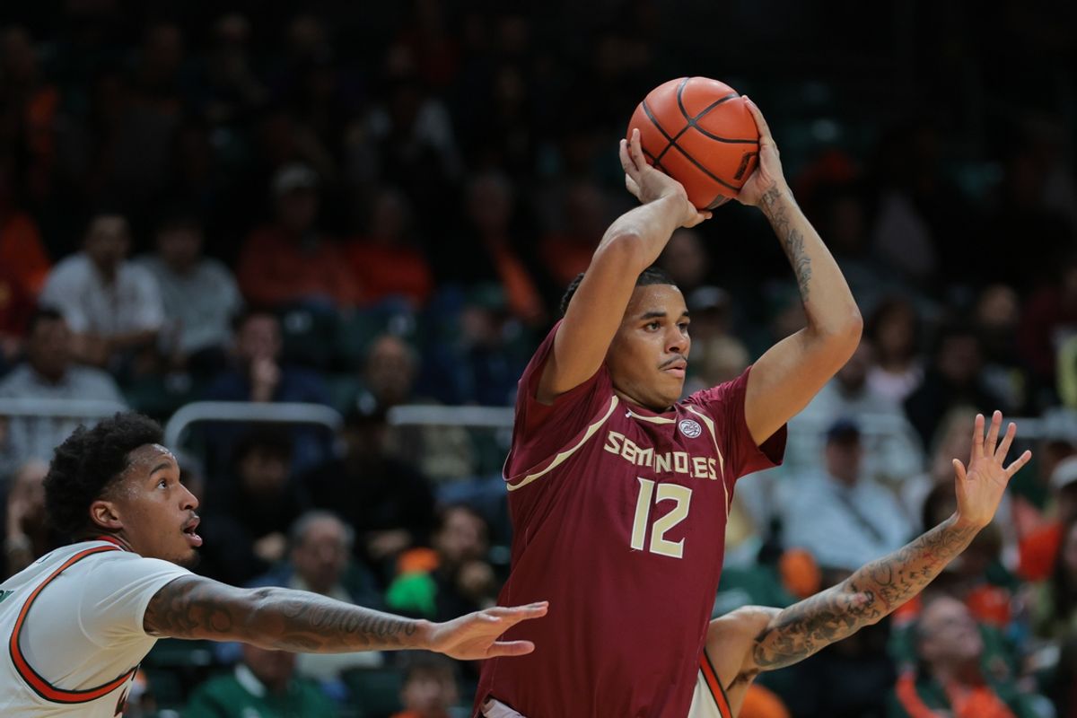 Jan 8, 2025; Coral Gables, Florida, USA; Florida State Seminoles forward Malique Ewin (12) passes the ball as Miami Hurricanes forward Brandon Johnson (2) defends during the first half at Watsco Center. Mandatory Credit: Sam Navarro-Imagn Images