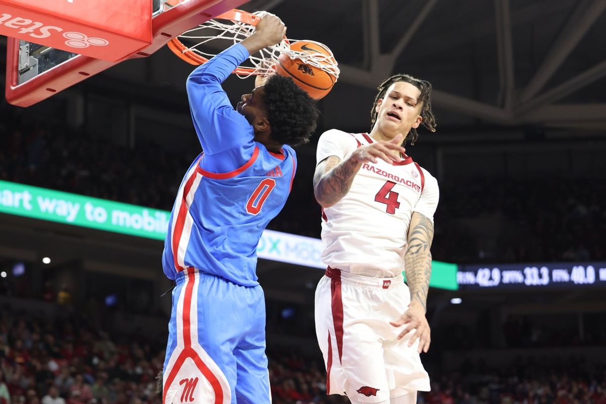 Jan 8, 2025; Fayetteville, Arkansas, USA; Ole Miss Rebels forward Malik Dia (0) dunks the ball as Arkansas Razorbacks forward Trevon Brazile (4) defends during the first half at Bud Walton Arena. Mandatory Credit: Nelson Chenault-Imagn Images