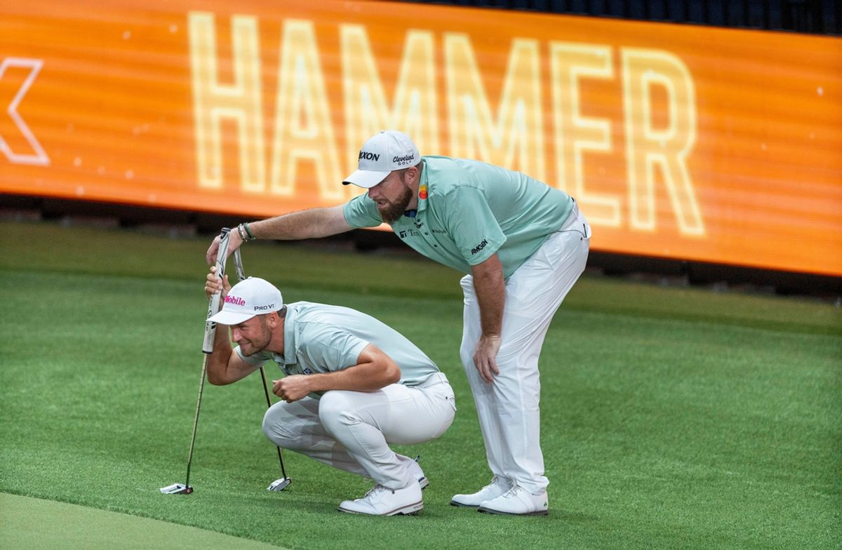 Bay Club golfer Shane Lowry, right, looks over the shoulder of his teammate Wyndham Clark as he lines up a putt during the inaugural TGL match at SoFi Center in Palm Beach Gardens, Florida.
