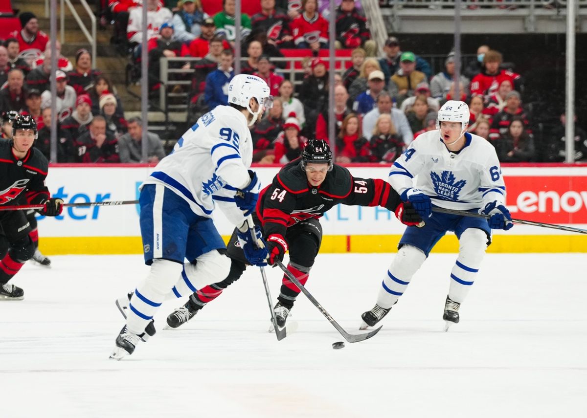 Jan 9, 2025; Raleigh, North Carolina, USA;  Toronto Maple Leafs defenseman Oliver Ekman-Larsson (95) with Toronto Maple Leafs center David Kampf (64) chases after the puck against Carolina Hurricanes left wing Juha Jaaska (54) during the first period at Lenovo Center. Mandatory Credit: James Guillory-Imagn Images