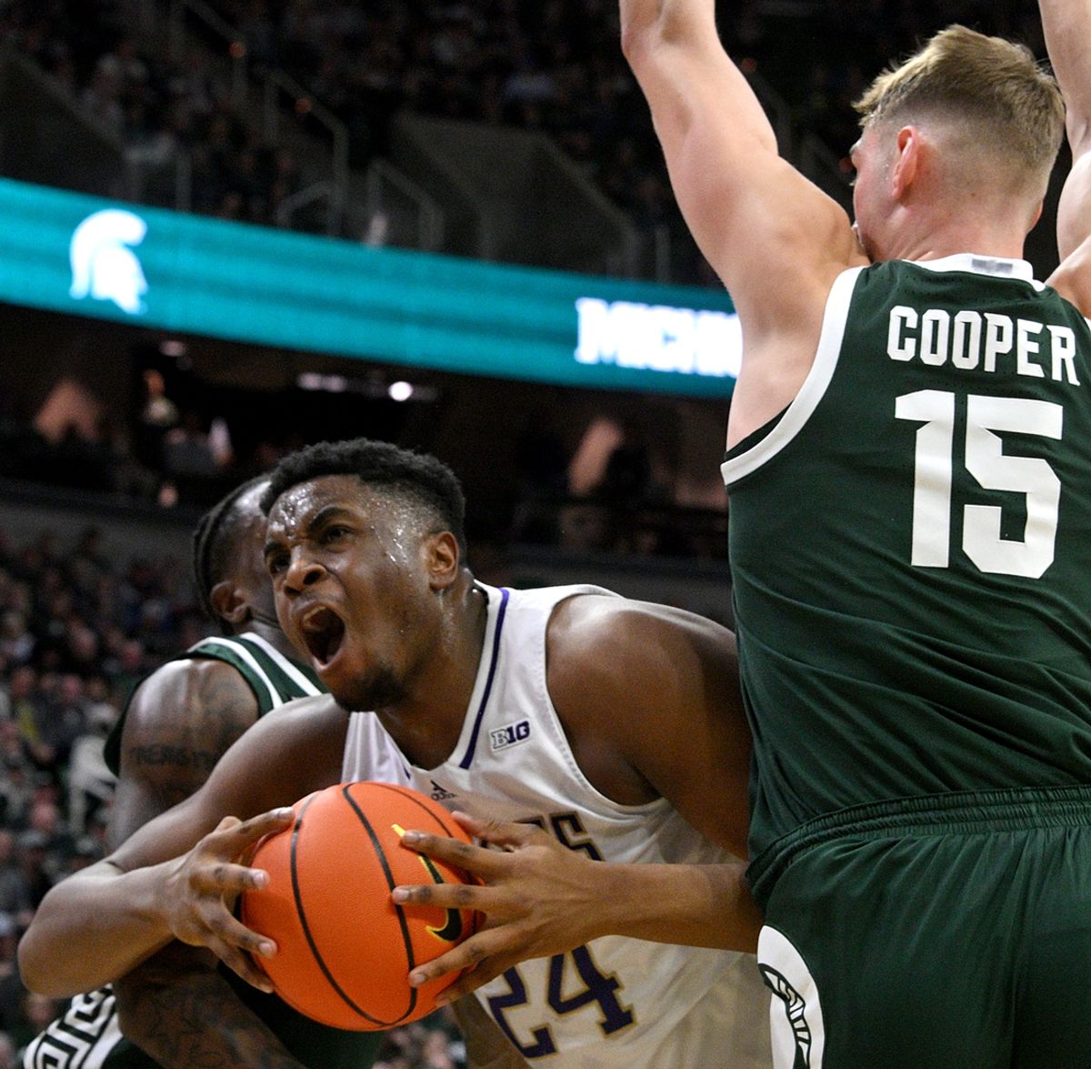 Jan 9, 2025; East Lansing, Michigan, USA;  Washington Huskies center KC Ibekwe (24) gets trapped by the Michigan State Spartans defense including Michigan State Spartans center Carson Cooper (15) during the first half at Jack Breslin Student Events Center. Mandatory Credit: Dale Young-Imagn Images