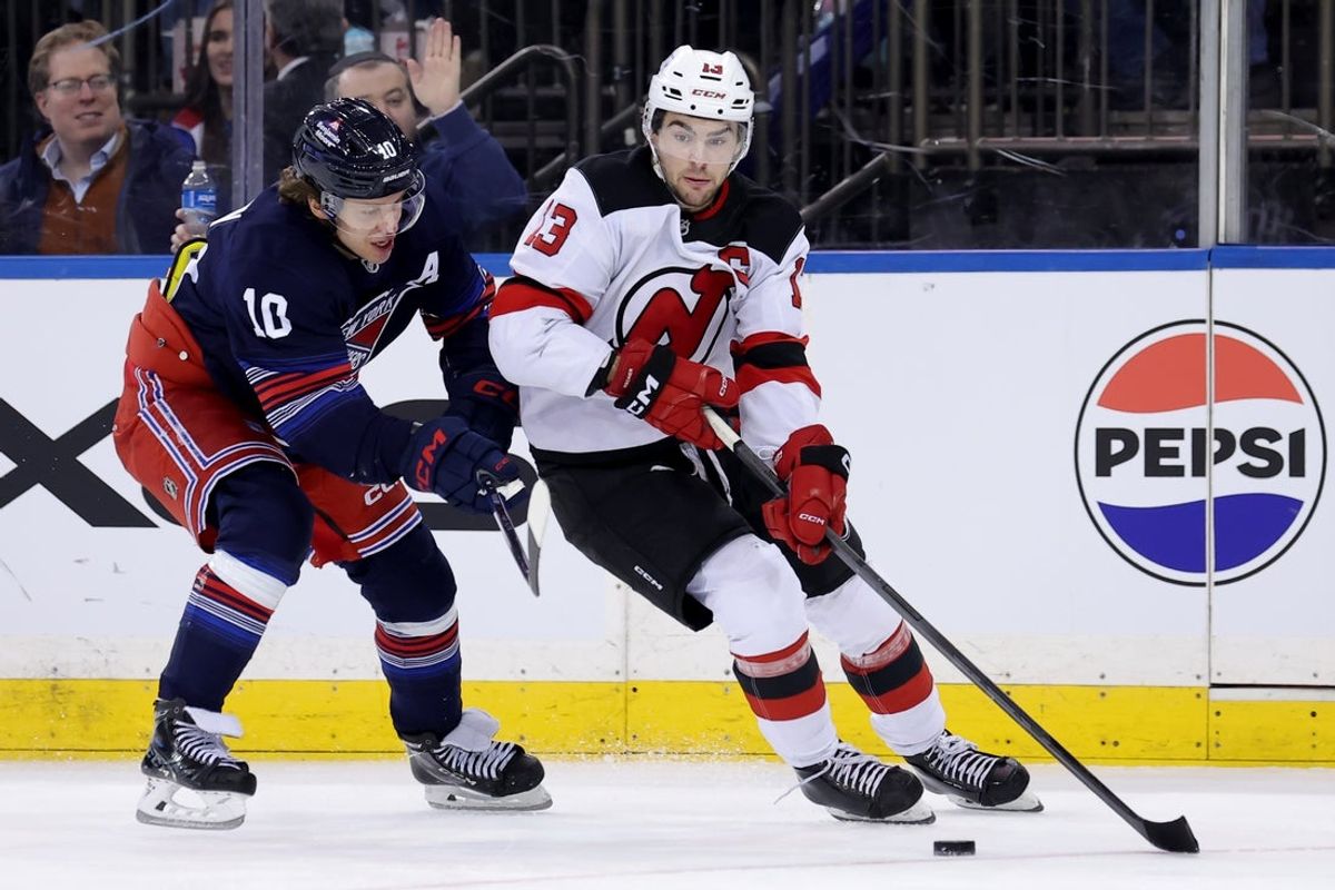 Jan 9, 2025; New York, New York, USA; New Jersey Devils center Nico Hischier (13) skates with the puck against New York Rangers left wing Artemi Panarin (10) during the third period at Madison Square Garden. Mandatory Credit: Brad Penner-Imagn Images