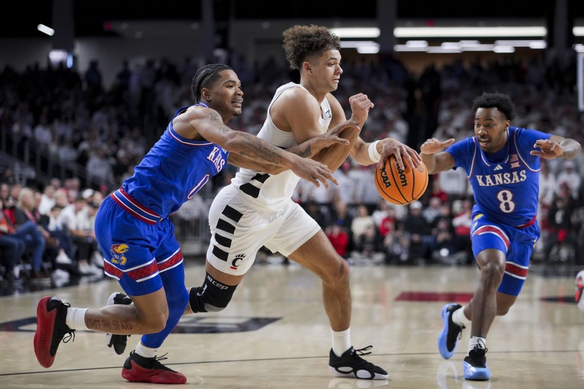 Jan 11, 2025; Cincinnati, Ohio, USA;  Cincinnati Bearcats guard Dan Skillings Jr. (0) dribbles the ball against Kansas Jayhawks guard Shakeel Moore (0) and guard David Coit (8) in the first half at Fifth Third Arena. Mandatory Credit: Aaron Doster-Imagn Images