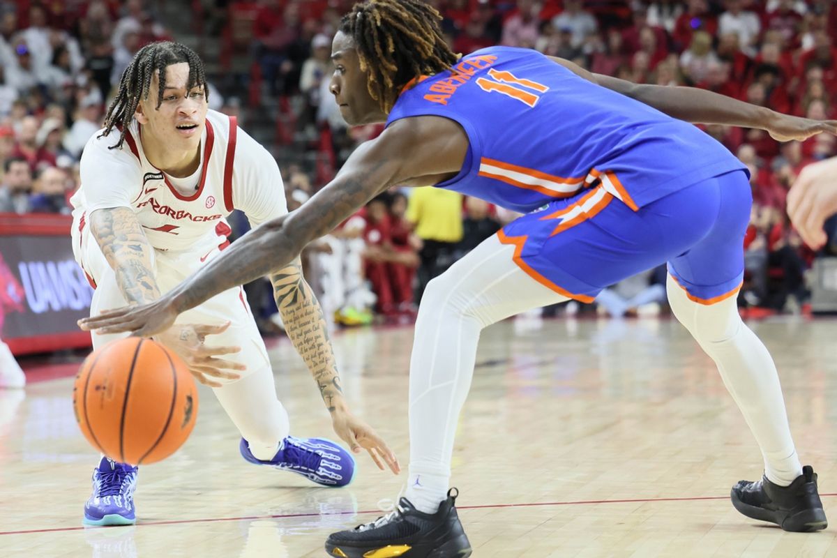 Jan 11, 2025; Fayetteville, Arkansas, USA; Arkansas Razorbacks forward Trevon Brazile (4) passes around Florida Gators guard Denzel Aberdeen (11) during the first half at Bud Walton Arena. Mandatory Credit: Nelson Chenault-Imagn Images