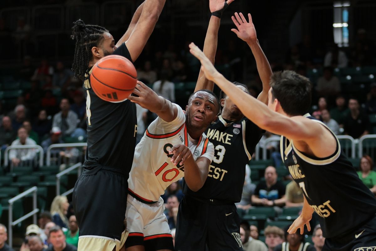 Jan 11, 2025; Coral Gables, Florida, USA; Miami Hurricanes guard Paul Djobet (10) passes the ball as Wake Forest Demon Deacons forward Efton Reid III (4) and guard Hunter Sallis (23) defend during the first half at Watsco Center. Mandatory Credit: Sam Navarro-Imagn Images