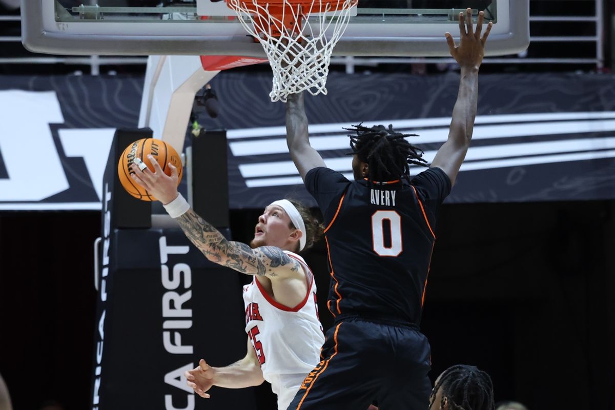 Jan 11, 2025; Salt Lake City, Utah, USA; Utah Utes guard Gabe Madsen (55) lays the ball up against Oklahoma State Cowboys forward Marchelus Avery (0) during the first half at Jon M. Huntsman Center. Mandatory Credit: Rob Gray-Imagn Images