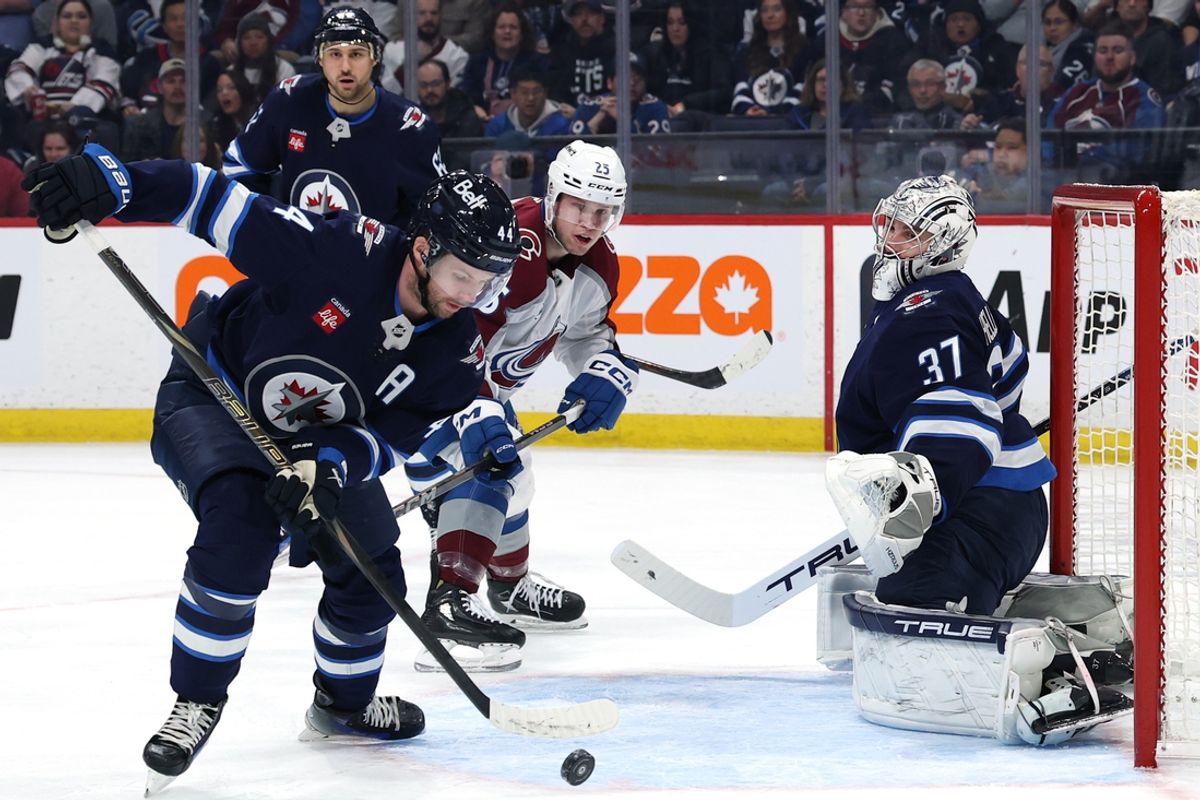 Jan 11, 2025; Winnipeg, Manitoba, CAN; Winnipeg Jets defenseman Josh Morrissey (44) clears the puck away form Winnipeg Jets goaltender Connor Hellebuyck (37) in the first period against the Colorado Avalanche at Canada Life Centre. Mandatory Credit: James Carey Lauder-Imagn Images