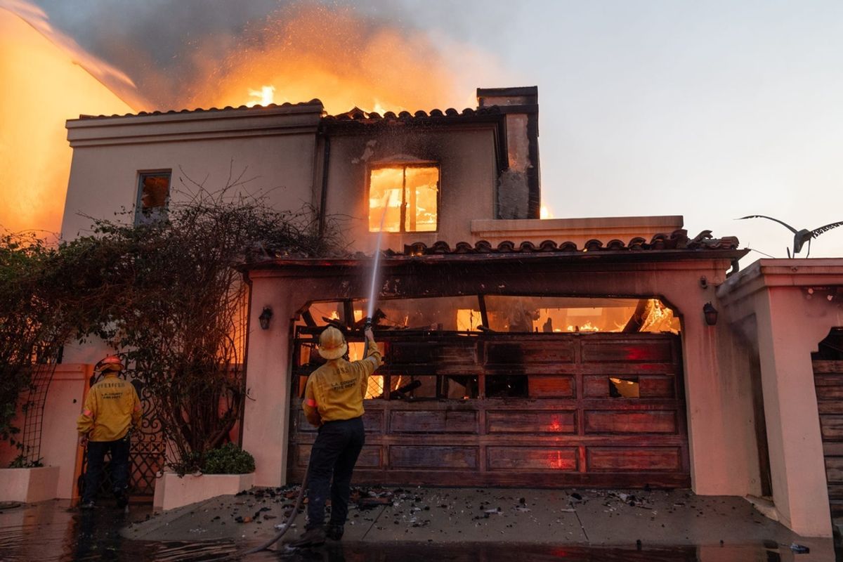 Firefighters attempt to extinguish a fire in a home along the Pacific Coast Highway in the Pacific Palisades neighborhood on Jan. 8, 2025. A wildfire broke out in Los Angeles County on Jan. 7, which has destroyed more than 1,000 homes, businesses and other structures, Los Angeles County Fire Chief Anthony Marrone said at a briefing Wednesday.