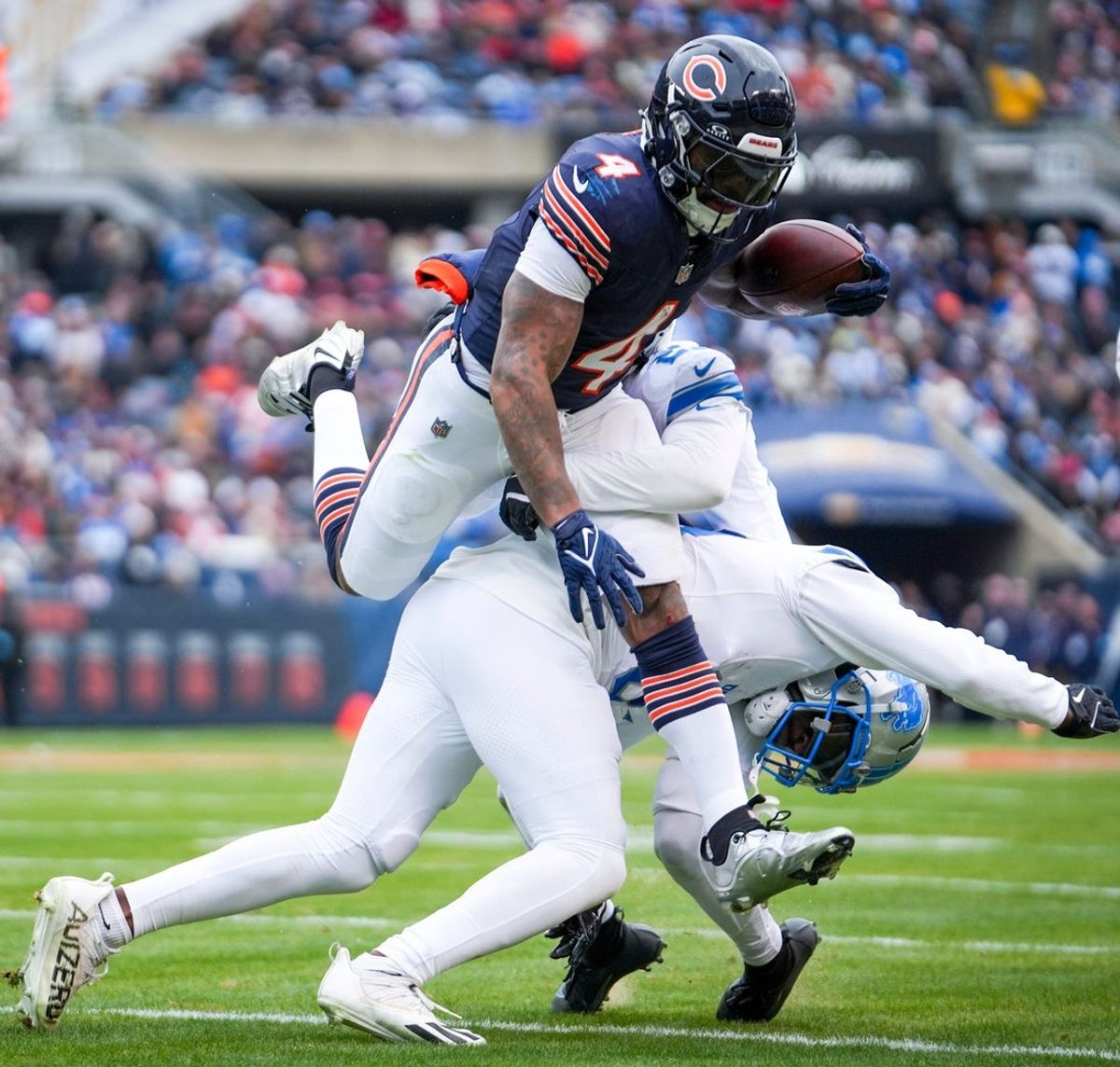 Chicago Bears running back D'Andre Swift (4) attempts to leap over Lions defense at Soldier Field during a game against the Chicago Bears at in Chicago, Ill., on Sunday, Dec. 22, 2024.