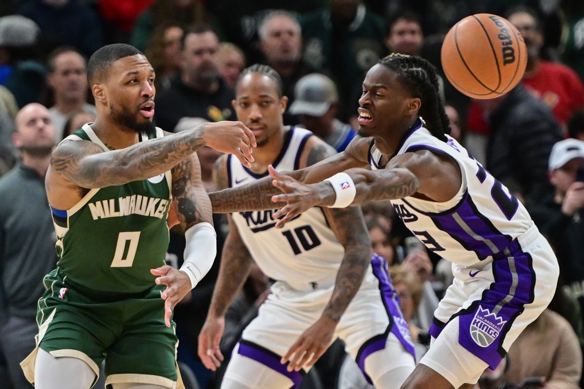 Jan 14, 2025; Milwaukee, Wisconsin, USA;  Milwaukee Bucks guard Damian Lillard (0) passes the ball away from Sacramento Kings forward DeMar DeRozan (10) and guard Keon Ellis (23) in the first quarter at Fiserv Forum. Mandatory Credit: Benny Sieu-Imagn Images