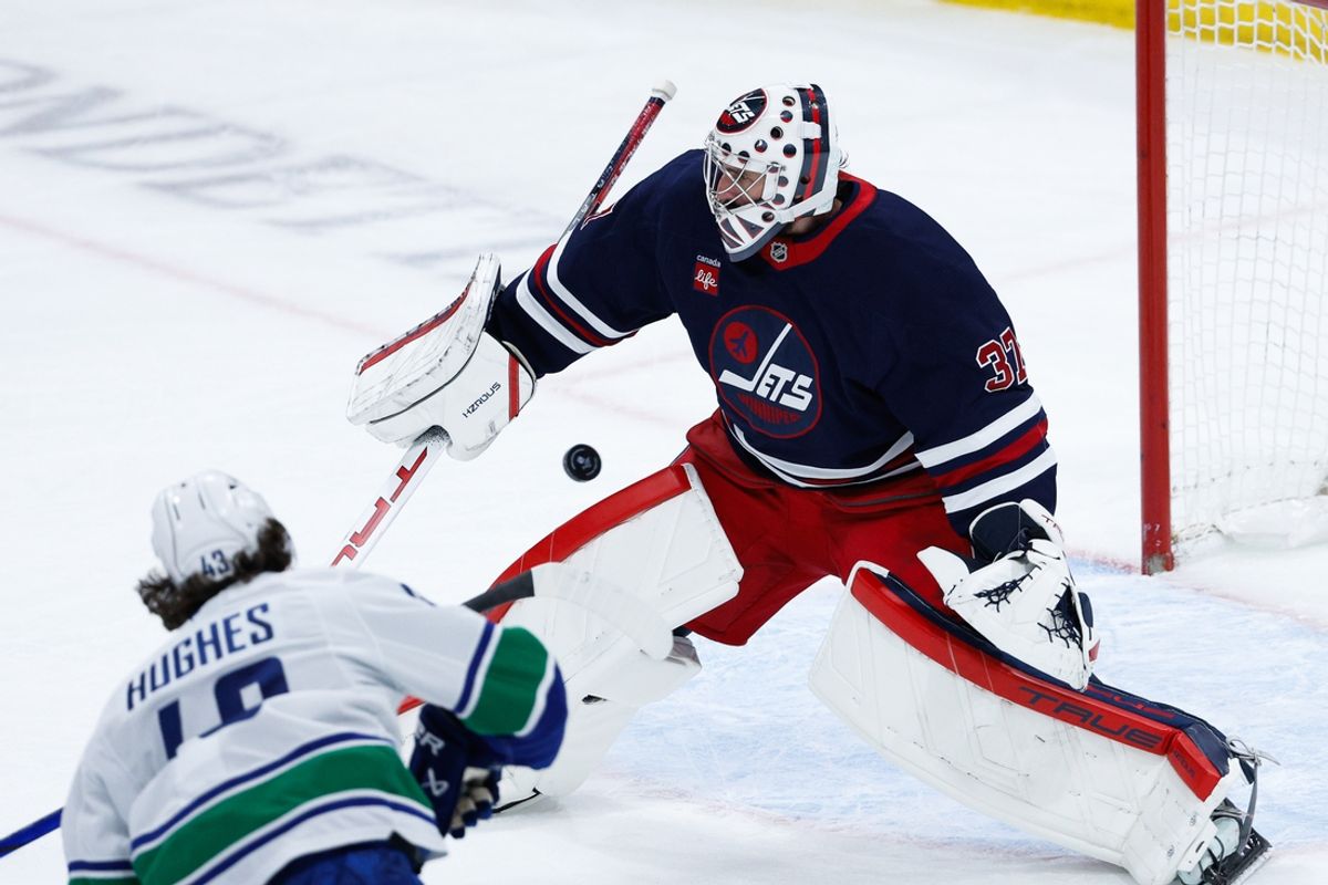 Jan 14, 2025; Winnipeg, Manitoba, CAN;  Winnipeg Jets goalie Connor Hellebuyck (37) makes a save on a shot by Vancouver Canucks defenseman Quinn Hughes (43) during the third period at Canada Life Centre. Mandatory Credit: Terrence Lee-Imagn Images