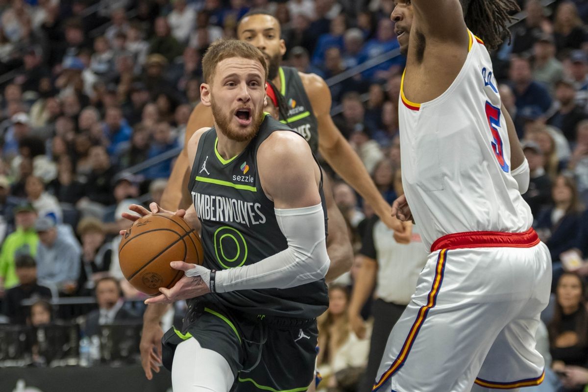 Jan 15, 2025; Minneapolis, Minnesota, USA; Minnesota Timberwolves guard Donte DiVincenzo (0) drives to the basket past Golden State Warriors forward Kevon Looney (5) in the first half at Target Center. Mandatory Credit: Jesse Johnson-Imagn Images