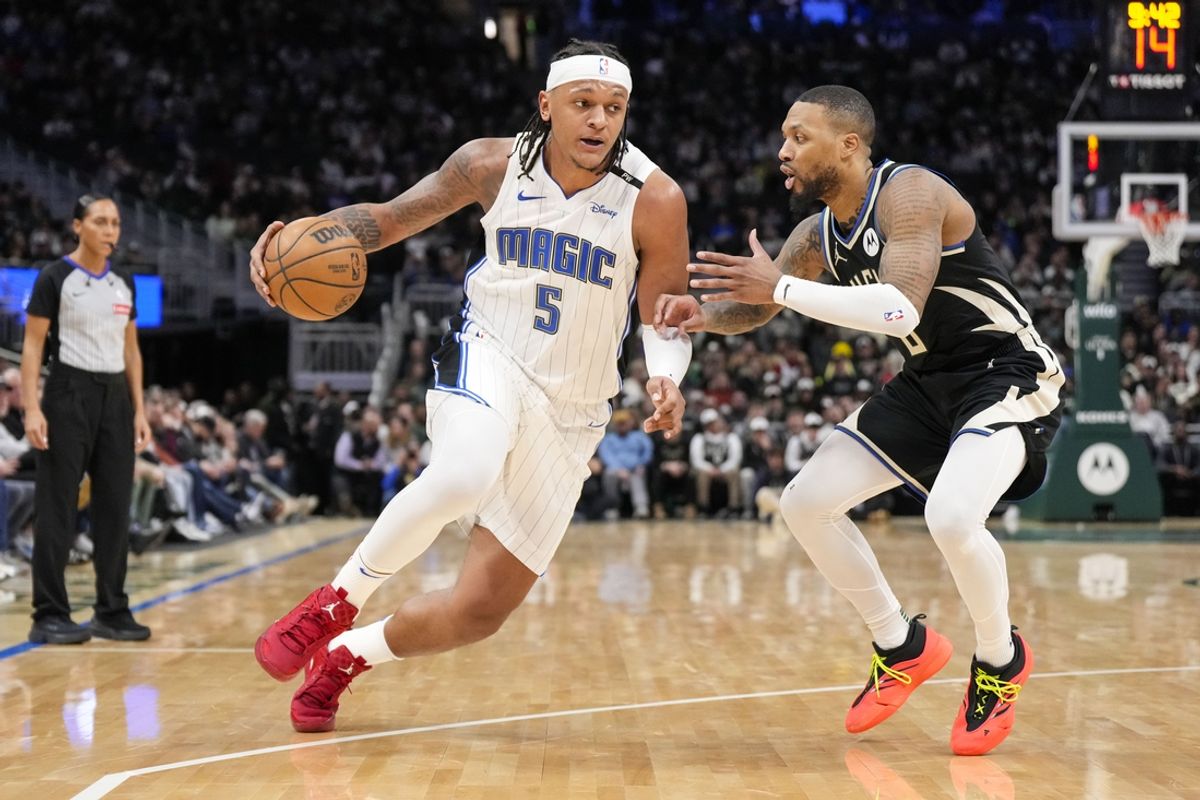 Jan 15, 2025; Milwaukee, Wisconsin, USA;  Orlando Magic forward Paolo Banchero (5) drives with the ball as Milwaukee Bucks guard Damian Lillard (0) defends during the fourth quarter at Fiserv Forum. Mandatory Credit: Jeff Hanisch-Imagn Images