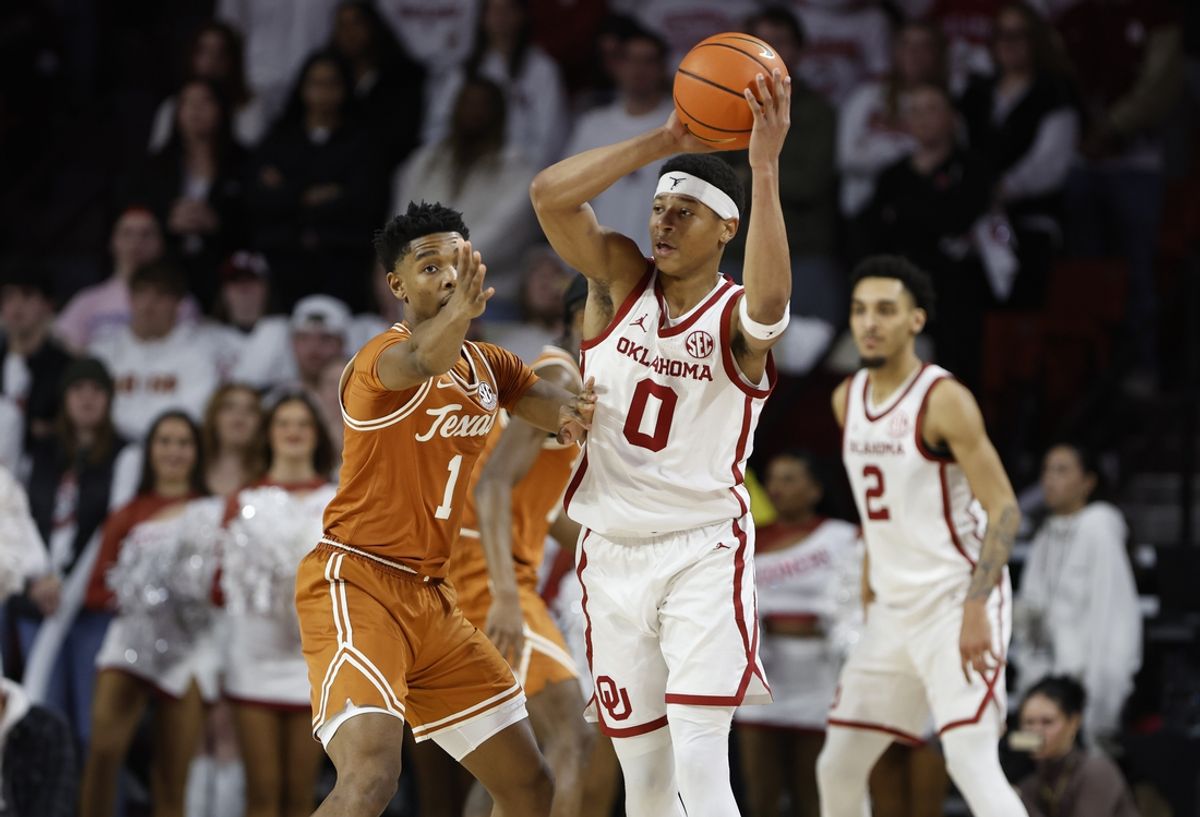 Jan 15, 2025; Norman, Oklahoma, USA; Oklahoma Sooners guard Jeremiah Fears (0) passes the ball around Texas Longhorns guard Julian Larry (1) during the first half at Lloyd Noble Center. Mandatory Credit: Alonzo Adams-Imagn Images
