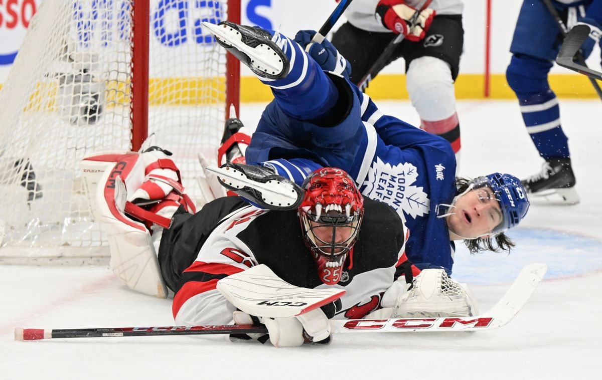 Jan 16, 2025; Toronto, Ontario, CAN;  Toronto Maple Leafs forward Matthew Knies (23) falls over New Jersey Devils goalie Jacob Markstrom (25) in the first period at Scotiabank Arena. Mandatory Credit: Dan Hamilton-Imagn Images