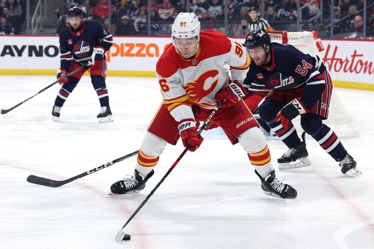 Jan 18, 2025; Winnipeg, Manitoba, CAN; Calgary Flames left wing Andrei Kuzmenko (96) is checked by Winnipeg Jets defenseman Dylan Samberg (54) in the first period at Canada Life Centre. Mandatory Credit: James Carey Lauder-Imagn Images