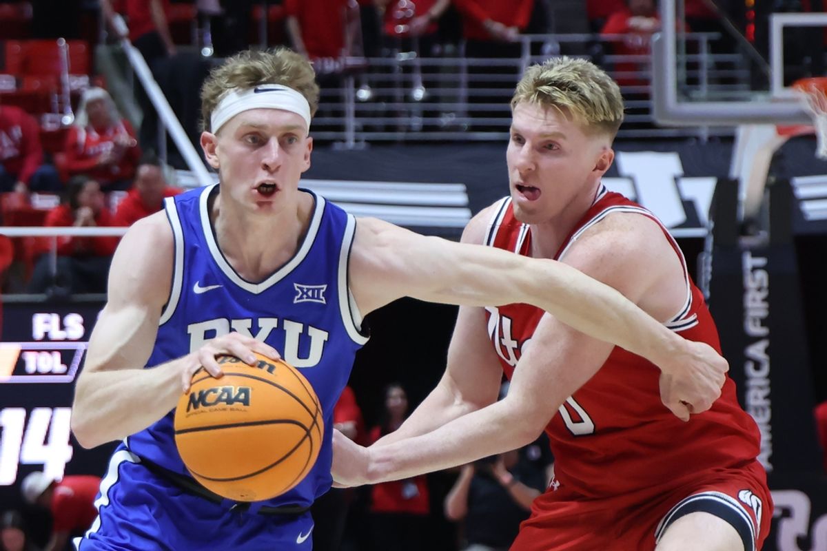 Jan 18, 2025; Salt Lake City, Utah, USA; Brigham Young Cougars forward Richie Saunders (left) drives against Utah Utes guard Hunter Erickson (0) during the first half at Jon M. Huntsman Center. Mandatory Credit: Rob Gray-Imagn Images