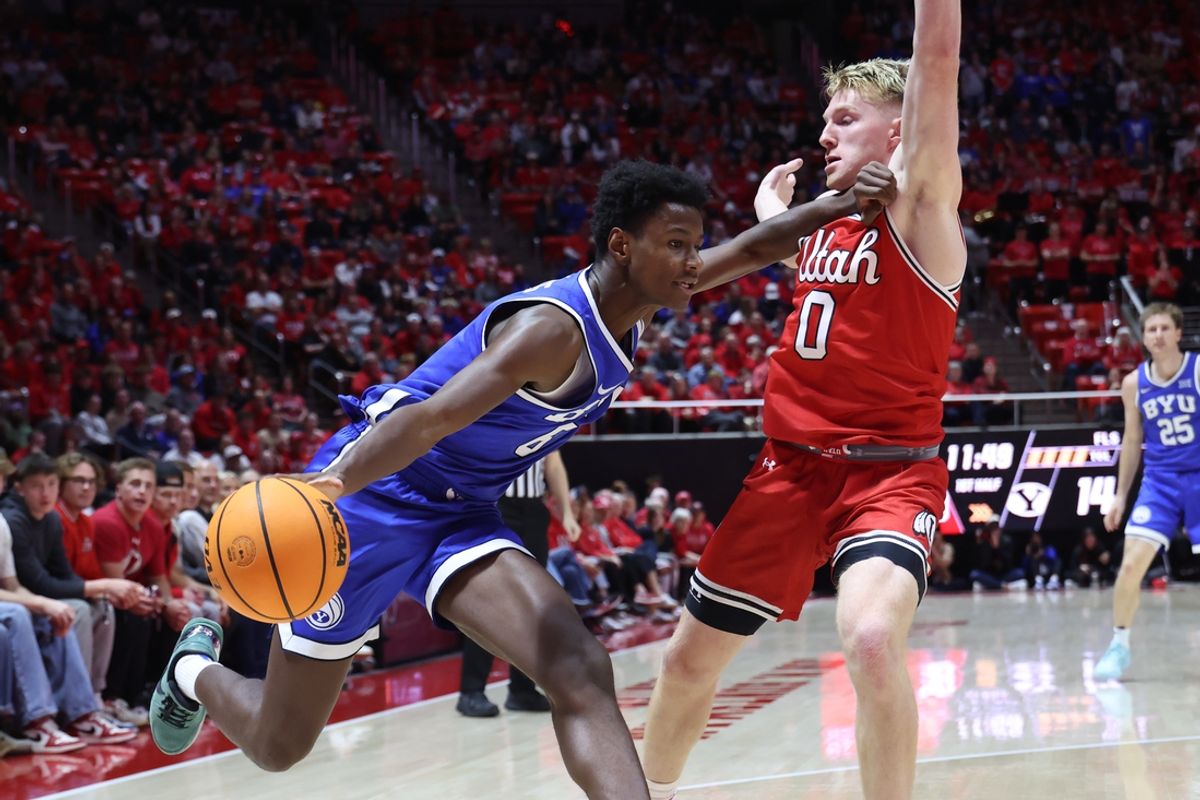Jan 18, 2025; Salt Lake City, Utah, USA; Brigham Young Cougars forward Kanon Catchings (6) drives against Utah Utes guard Hunter Erickson (0) during the first half at Jon M. Huntsman Center. Mandatory Credit: Rob Gray-Imagn Images