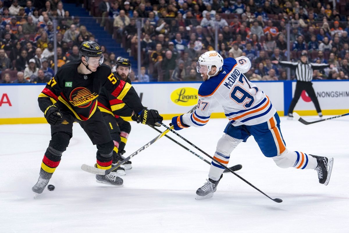 Jan 18, 2025; Vancouver, British Columbia, CAN; Edmonton Oilers forward Connor McDavid (97) shoots around Vancouver Canucks defenseman Tyler Myers (57) in the first period at Rogers Arena. Mandatory Credit: Bob Frid-Imagn Images