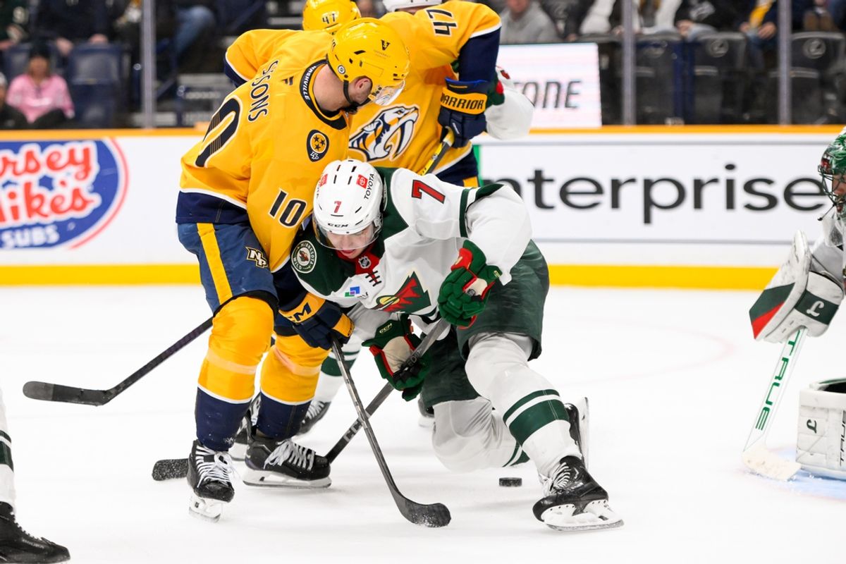 Jan 18, 2025; Nashville, Tennessee, USA;  Nashville Predators center Colton Sissons (10) and Minnesota Wild defenseman Brock Faber (7) battle for the puck during the third period at Bridgestone Arena. Mandatory Credit: Steve Roberts-Imagn Images