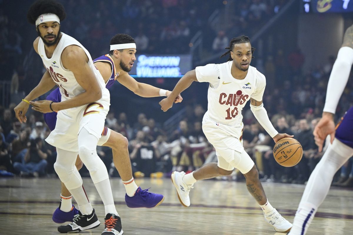 Jan 20, 2025; Cleveland, Ohio, USA; Cleveland Cavaliers guard Darius Garland (10) dribbles around center Jarrett Allen (31) and Phoenix Suns guard Devin Booker (1) in the first quarter at Rocket Mortgage FieldHouse. Mandatory Credit: David Richard-Imagn Images