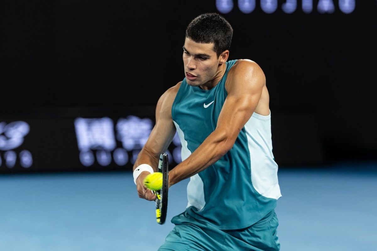 Jan 21, 2025; Melbourne, Victoria, Australia; Carlos Alcaraz of Spain plays a backhand during his match against Novak Djokovic of Serbia in the quarterfinals of the men's singles at the 2025 Australian Open at Melbourne Park. Mandatory Credit: Mike Frey-Imagn Images